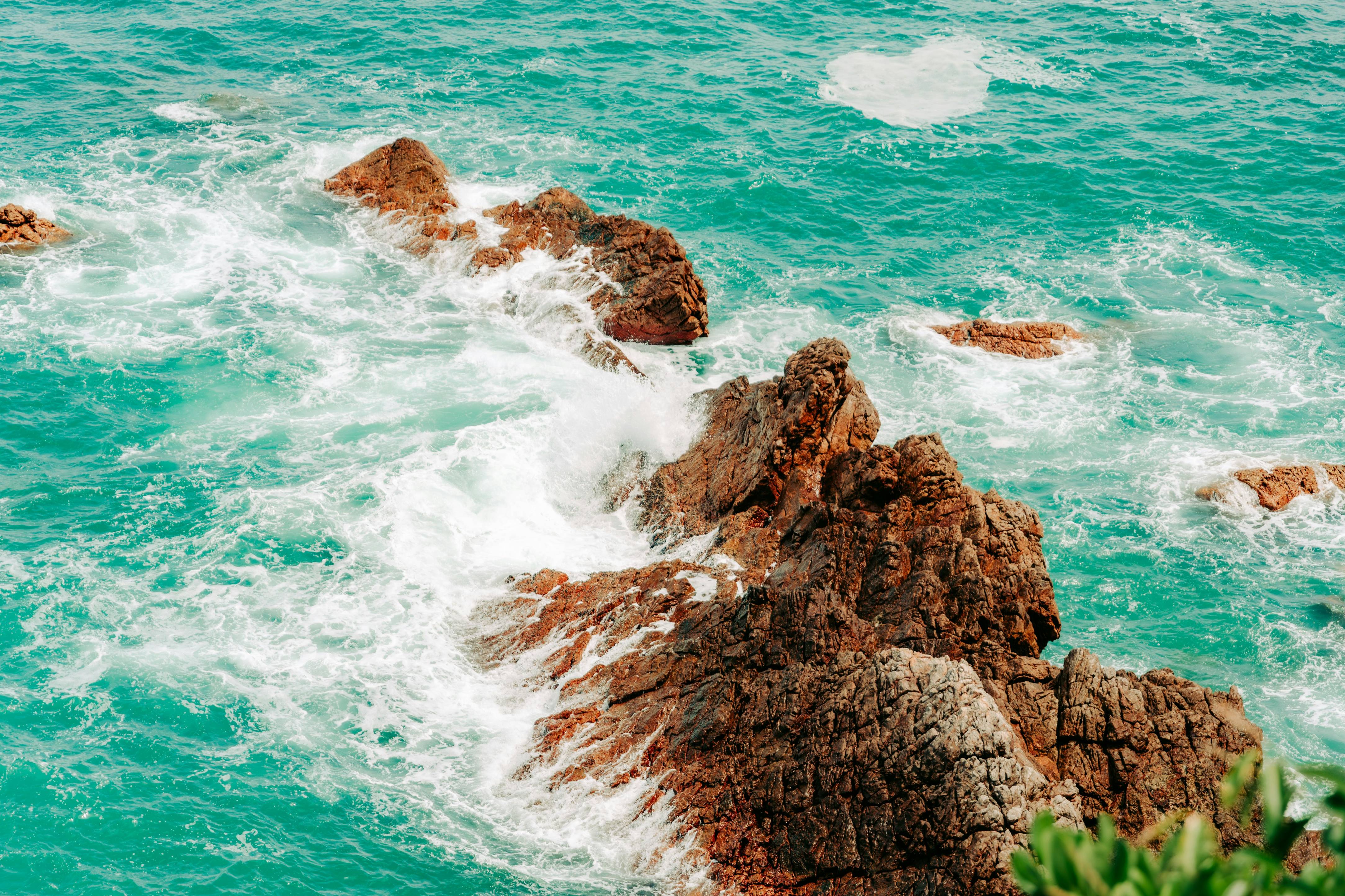 Waves crash against rocky cliffs in the ocean.