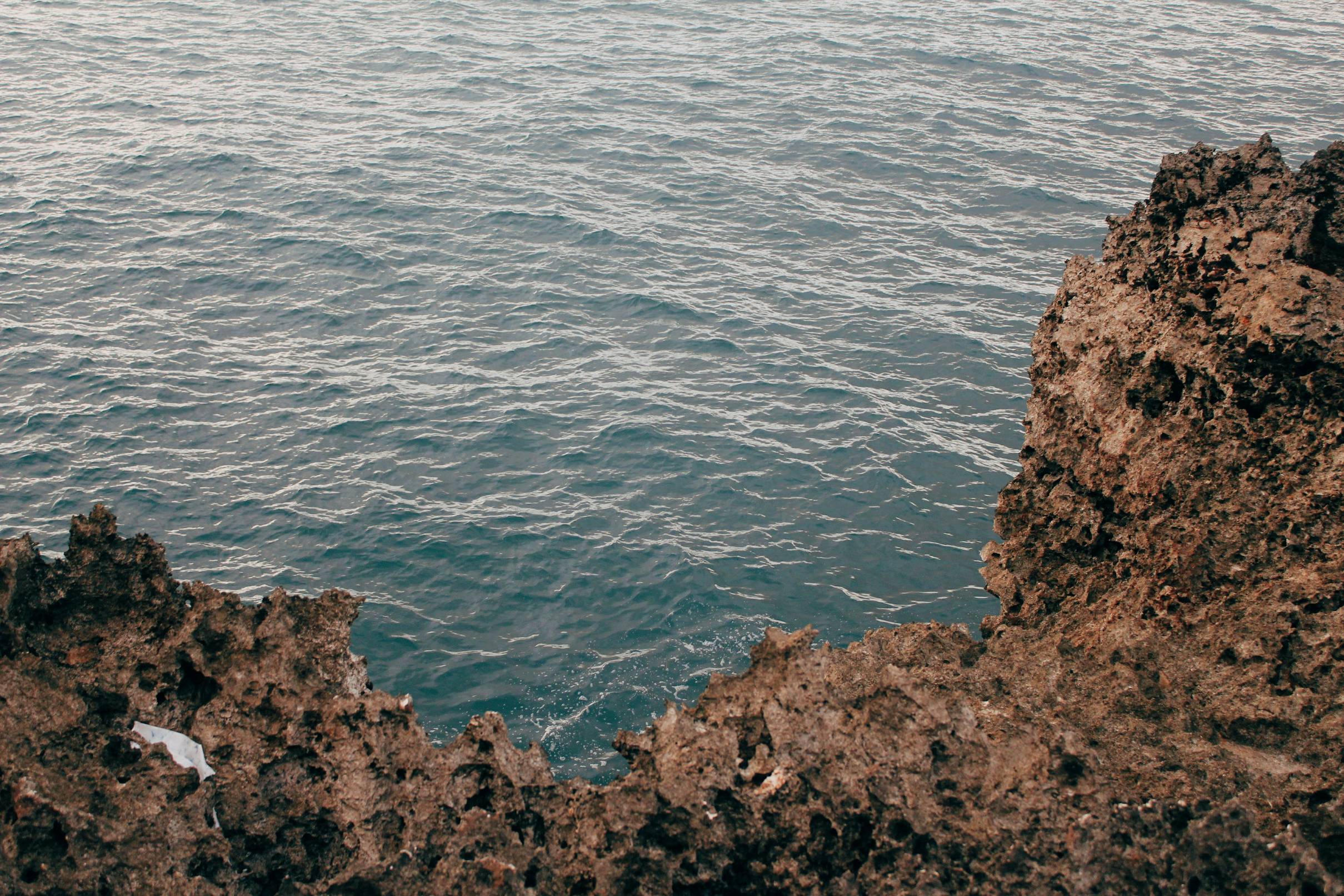 brown rock formation beside body of water during daytime