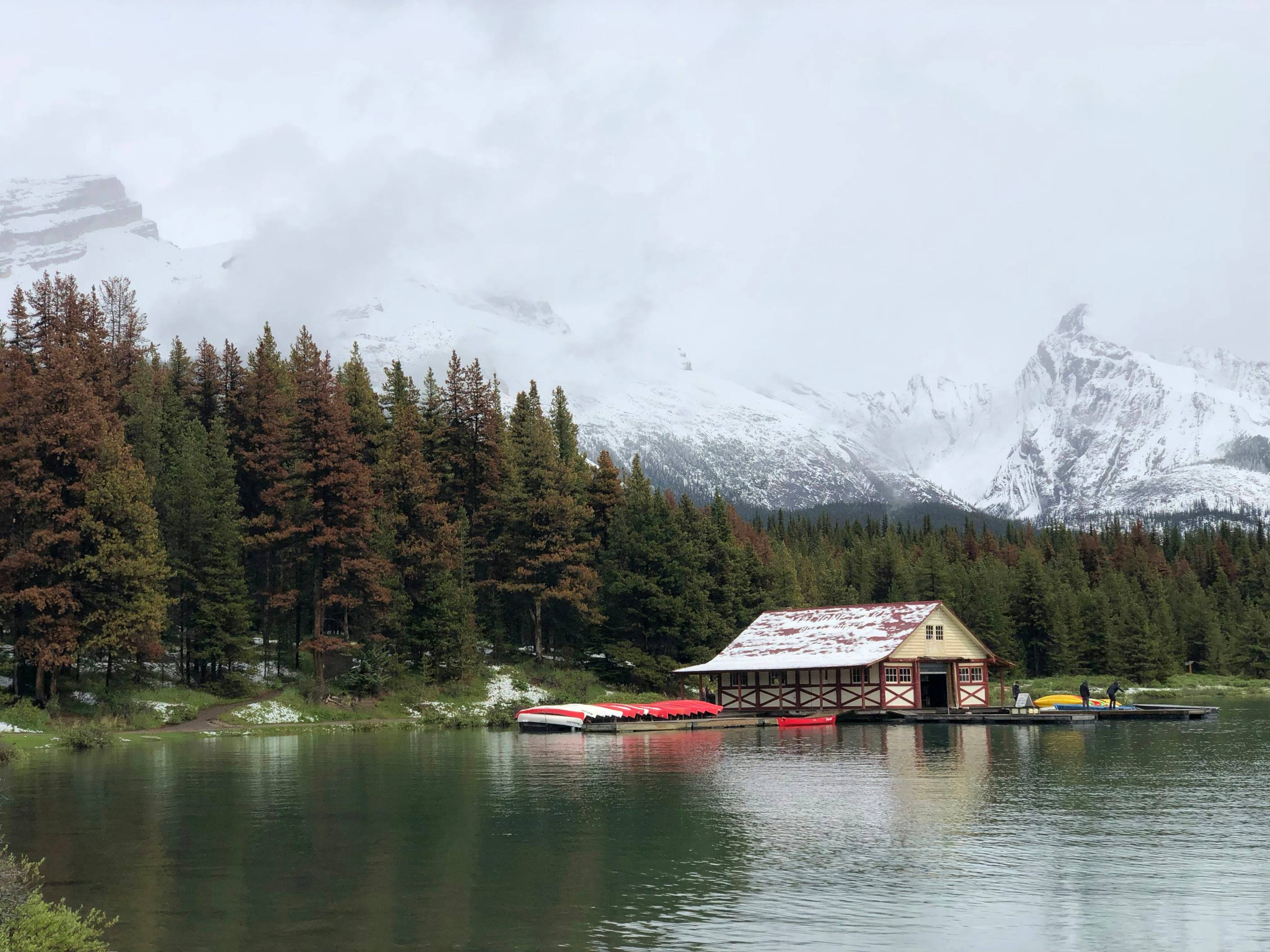 a boat house on a lake with mountains in the background