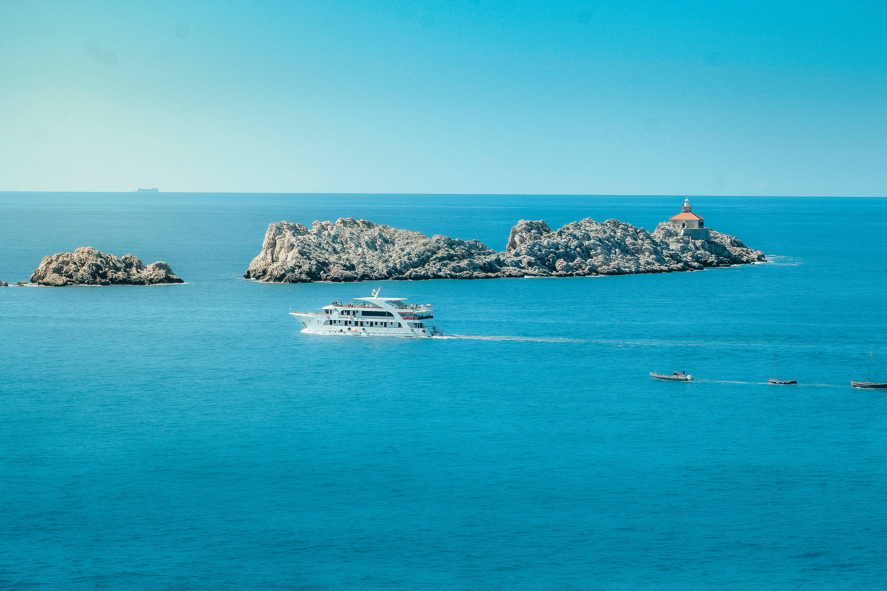A large white boat sails across the blue ocean.